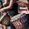 people playing goblet drums during daytime